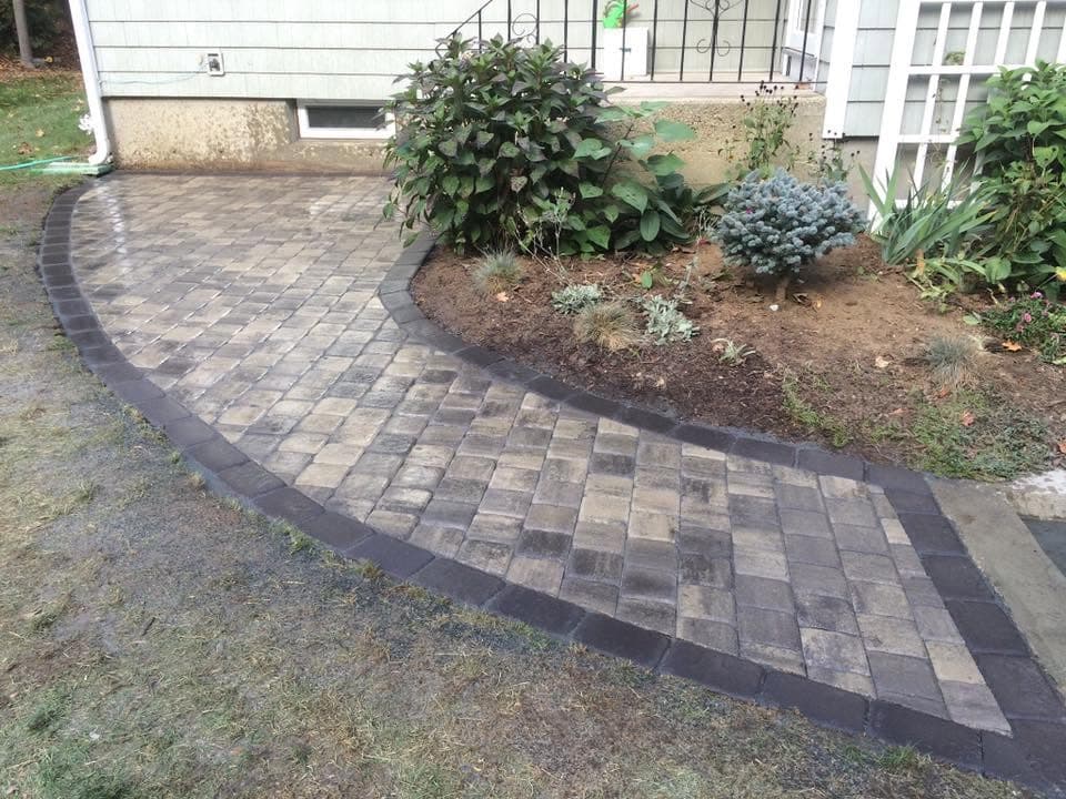 Curved paver walkway with a charcoal soldier border running alongside a planting bed.